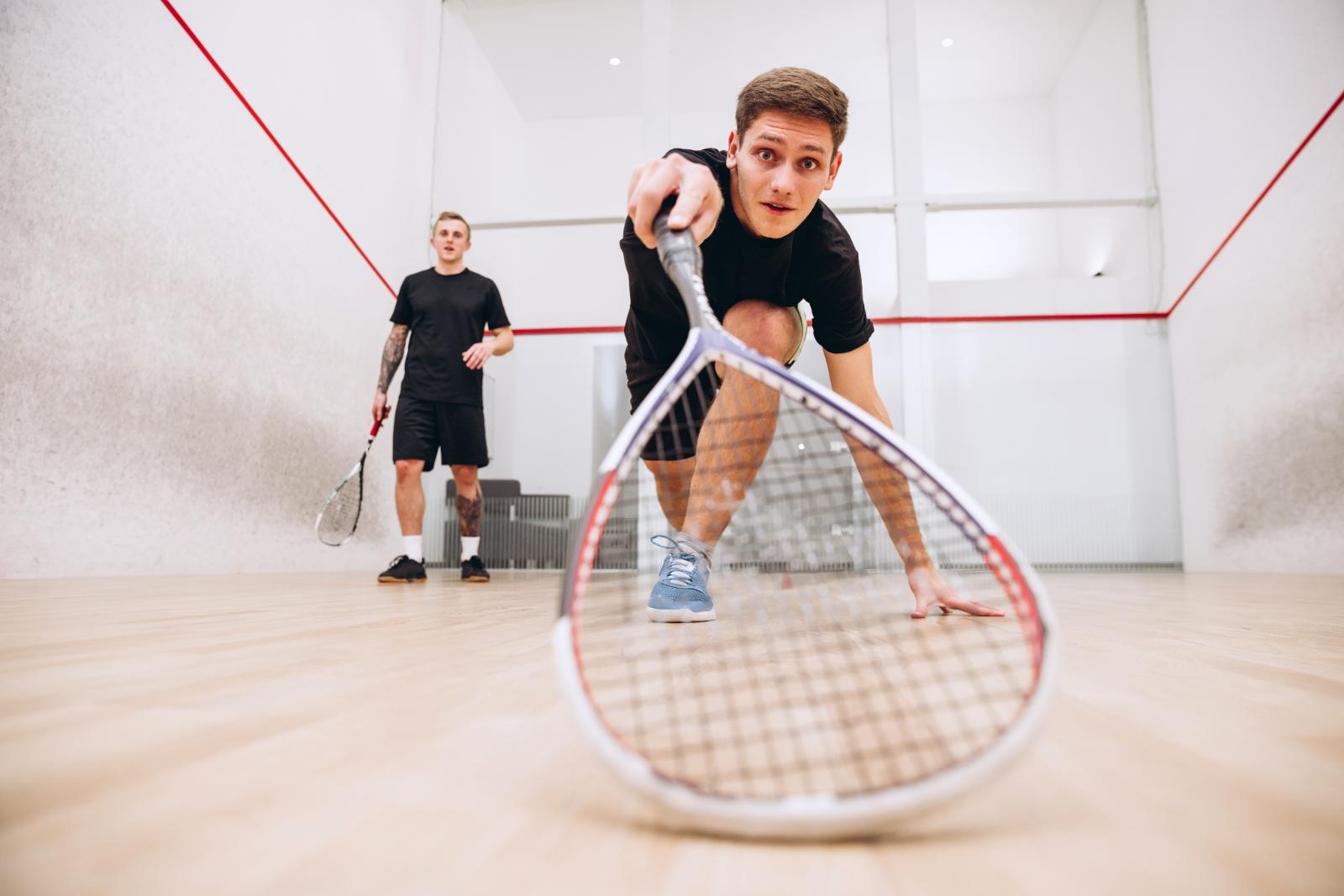Spieler geht tief in die Hocke, den Blick fest auf den Ball, der Schläger ragt groß in den Vordergrund